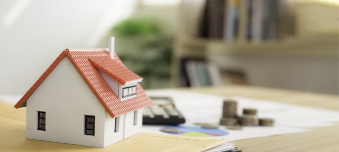 A small toy house on a table with other desk items