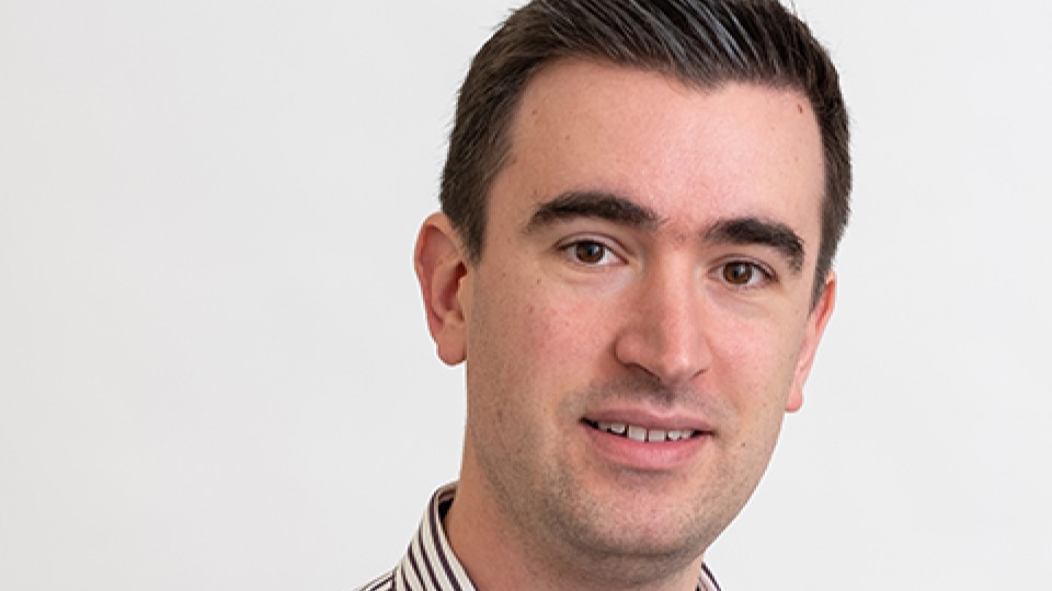 Dr Marjoribanks with striped shirt collar facing the camera smiling