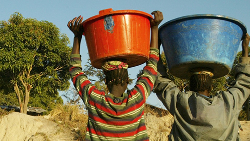 A woman carrying water in a bucket on her head