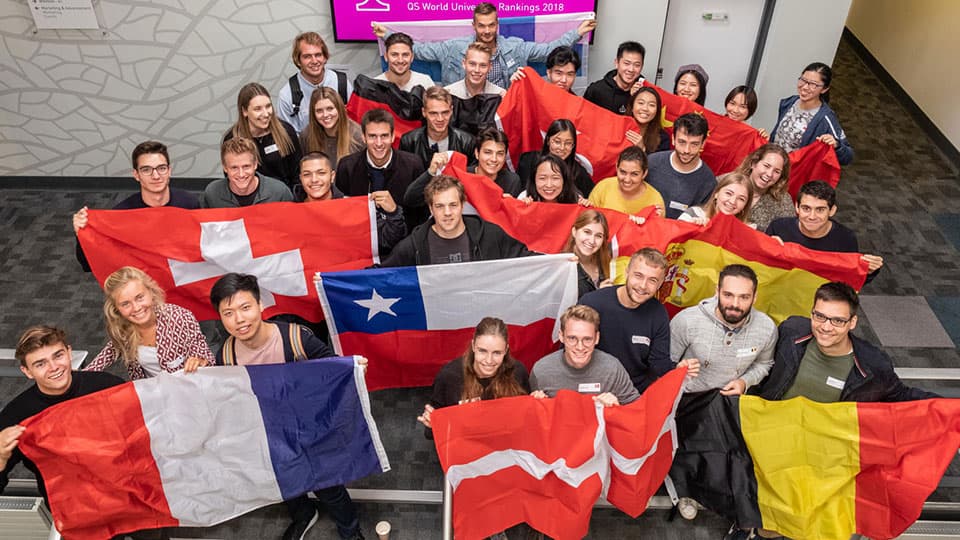 Study exchange students gathered together holding the flags of their home countries.