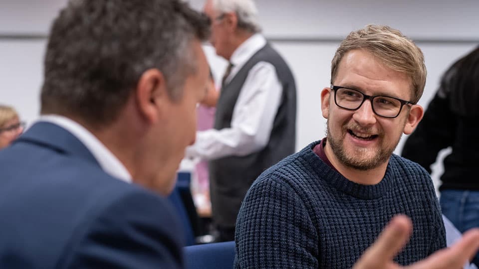 Two people talking and smiling at an executive education workshop.
