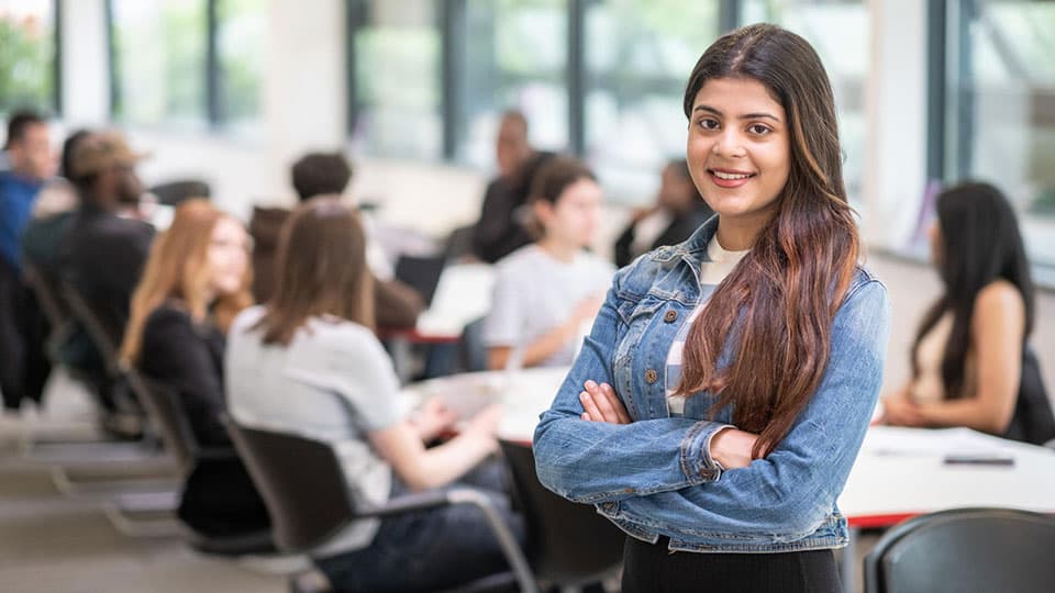 An undergraduate student stood up with arms folded facing the camera