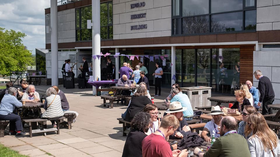 Groups of people sat outside on benches.