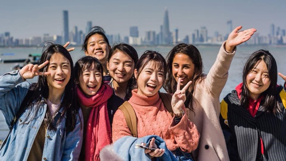 A group of students with a city skyline behind them.