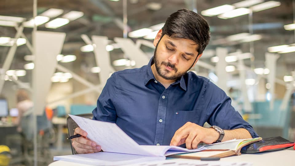 A student sat at a table looking at papers in the library.