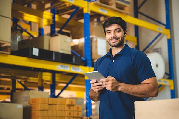 A person in a warehouse holding a tablet computer.