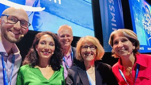 Professors Tom Jackson and Ian Hodgkinson with three other people at the HIMSS 2024 conference.