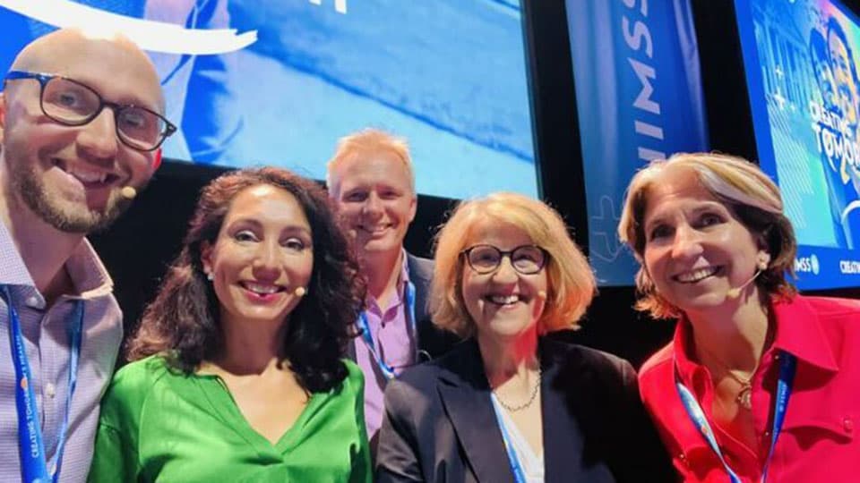 Professors Tom Jackson and Ian Hodgkinson with three other people at the HIMSS 2024 conference.