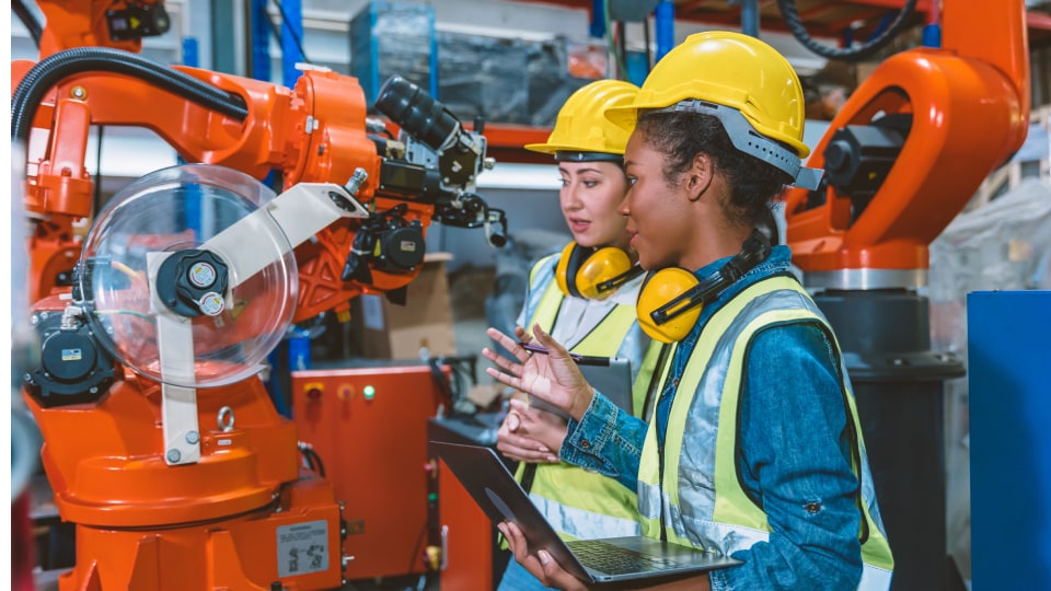Two people in hard hats and high visibility jackets in a manufacturing facility