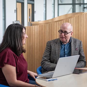 Two people sitting at a table talking.