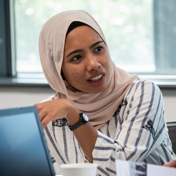 A woman using a laptop talking to another woman
