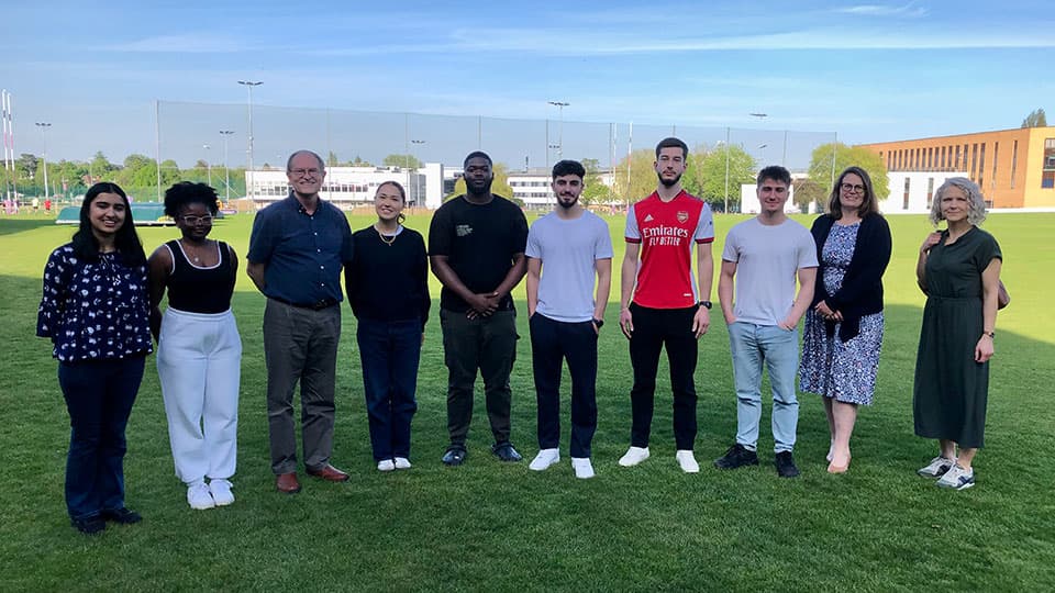 Professor Jeffrey Wooldridge with staff and students from Loughborough Business School standing outside on a green field.