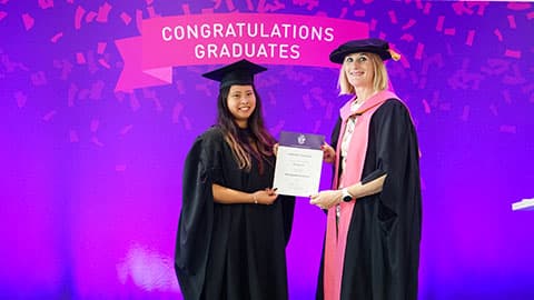 Sophia Xiao Yang Doret on stage with their certificate from Professor Jan Godsell.