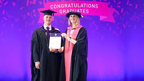 Jacob Elliott Phillips on stage with their certificate from Professor Jan Godsell.