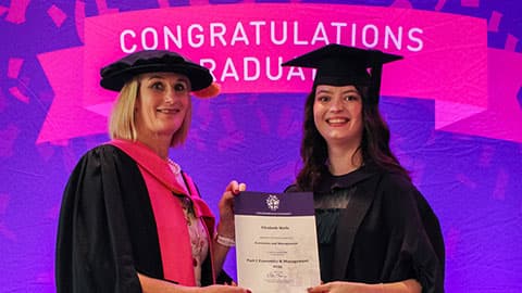 Elizabeth Wells on stage with their certificate from Professor Jan Godsell.