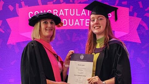 Niamh Cahill on stage with their certificate from Professor Jan Godsell.