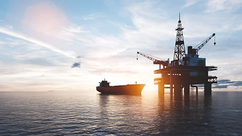 Oil platform on the ocean with a ship closeby.
