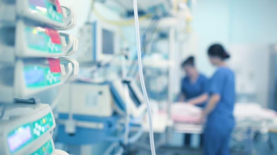 Two medical staff arranging a bed in a hospital room.
