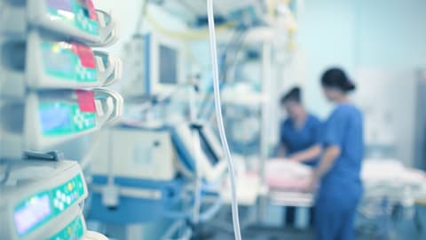 Two medical staff arranging a bed in a hospital room.