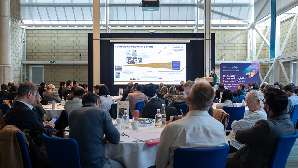 Attendees seated in a conference hall listening to a presentation during the UK Academic Supply Chain Network event.