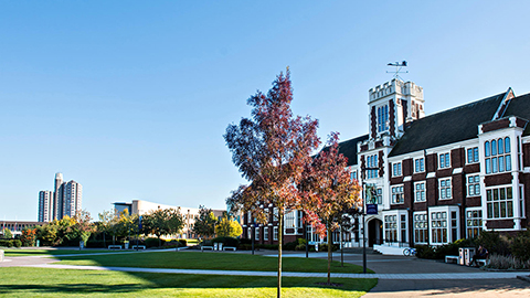 Hazlerigg building with autumn tree, and modern buildings in background.