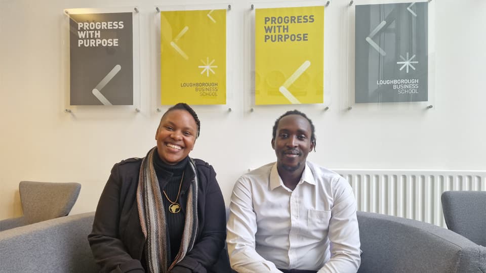 Serah Muindi and Carson Keago sitting on a sofa in the Loughborough Business School building.