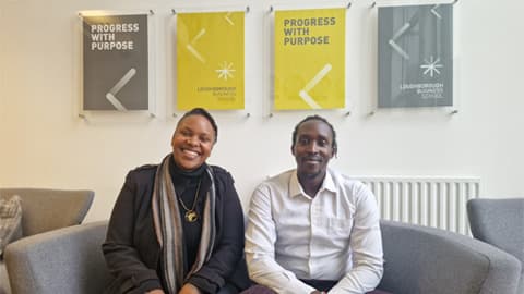 Serah Muindi and Carson Keago sitting on a sofa in the Loughborough Business School building.