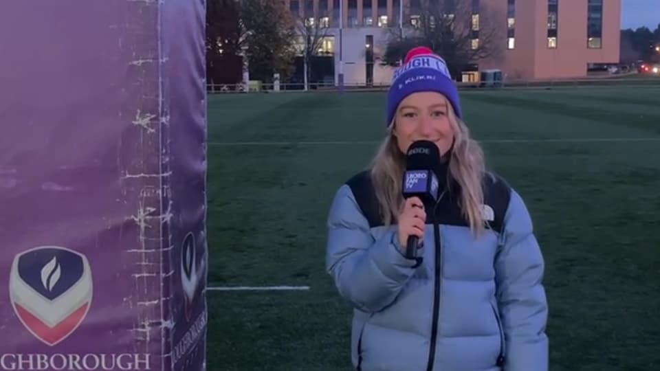Bella Harris-Johnstone standing outside on a sports pitch with a microphone.