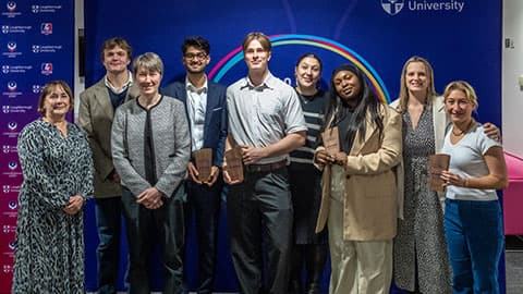 A group of staff and students standing in front of a banner.