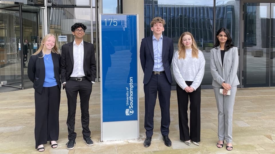 Five students dressed smartly standing next to a University of Southampton sign.