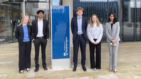 Five students dressed smartly standing next to a University of Southampton sign.