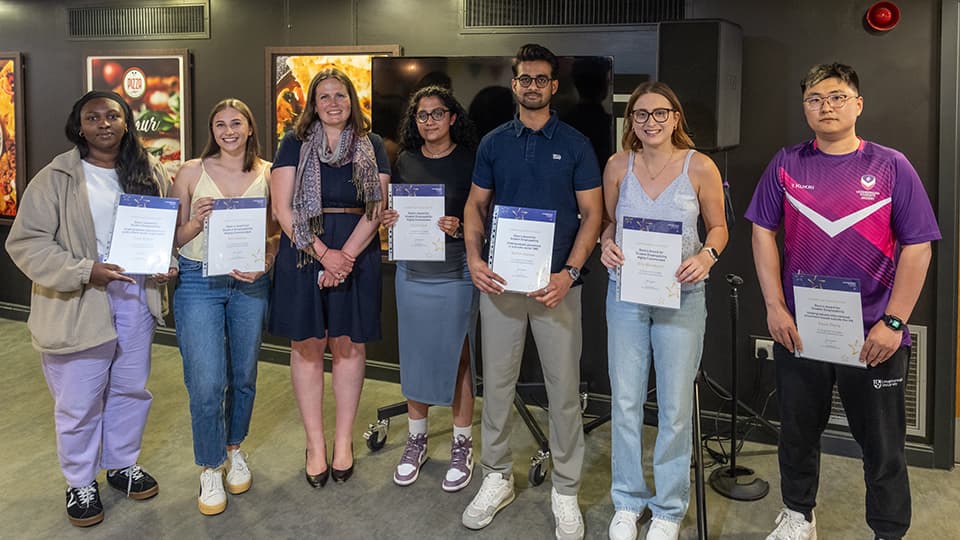 A group of student award winners standing in a row holding their certificates.