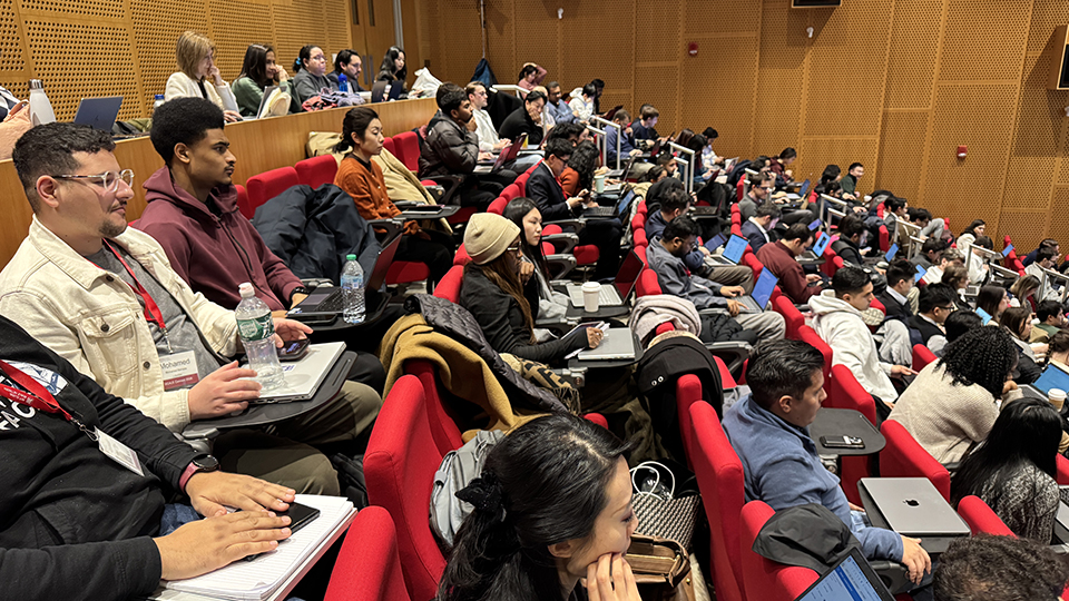 Students seated in a large MIT lecture theatre, listening to a session during the SCALE Connect Residential, with laptops and notebooks open.