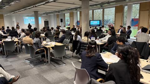 A large room filled with groups of students sat at tables during the UBC semi-final.