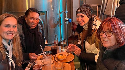Ekaterina with a group of three other people sitting down having a meal.