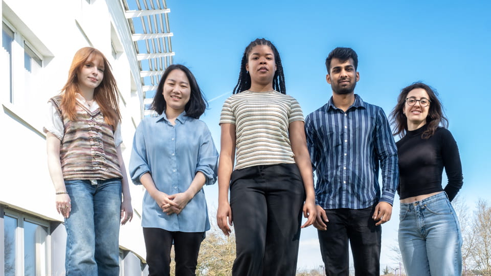 Five members of the Research Group standing in a line outside the Business School building