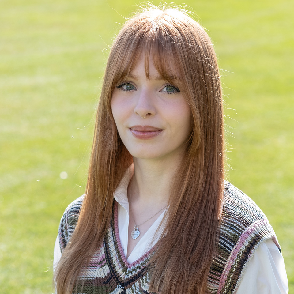 A portrait of Emily Cox standing on grass