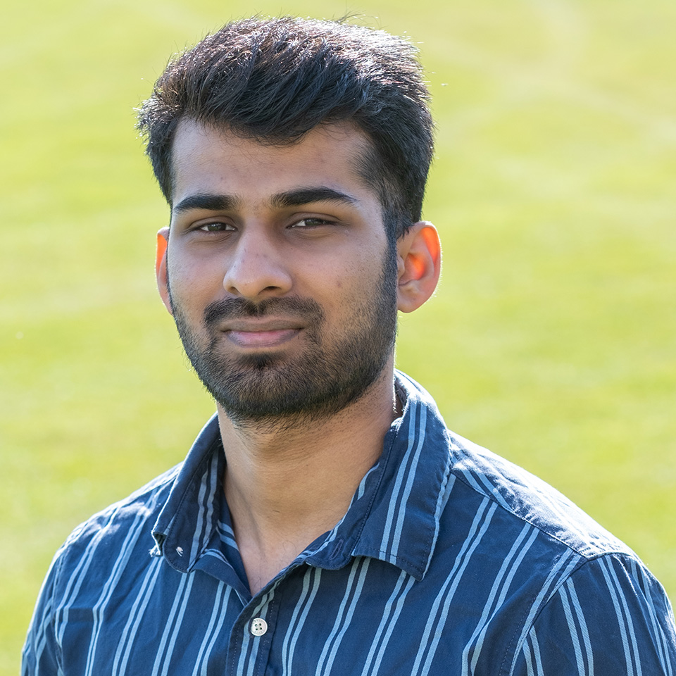A portrait of Inish D-Souza standing on grass
