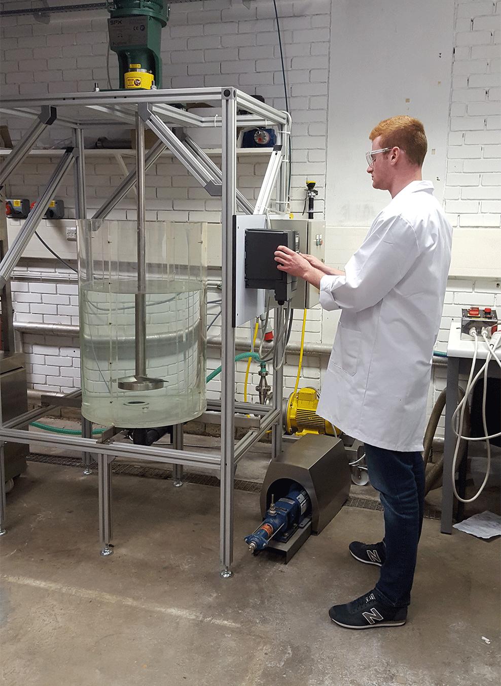 A researcher in a lab coat working with a stirred tank