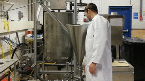 Researcher in a lab coat with materials tank