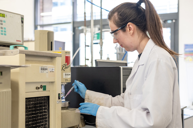 Lisa working in lab using a pipette and microscope.