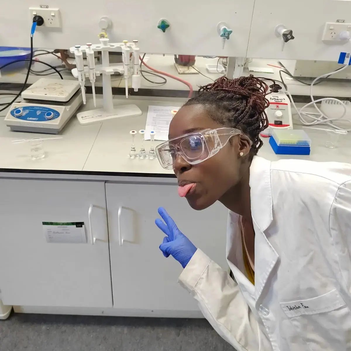 Uche in a lab wearing goggles and lab coat