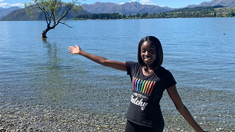 Uche standing in front of a lake with her arms open