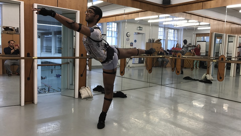 A man in a ballet position wearing wireless motion sensors.