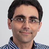 A headshot of Hossein Nevisi wearing glasses and a striped shirt