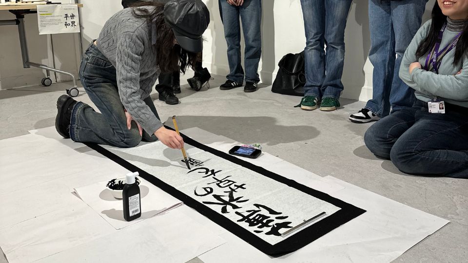 Visitors observing Japanese calligraphy workshop