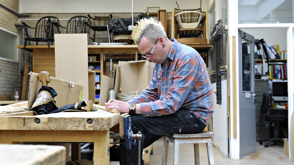 A student sitting and completing a woodwork task