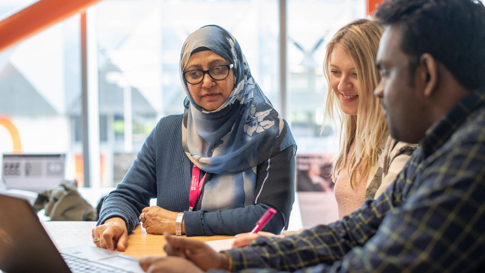 Students being supported around a laptop