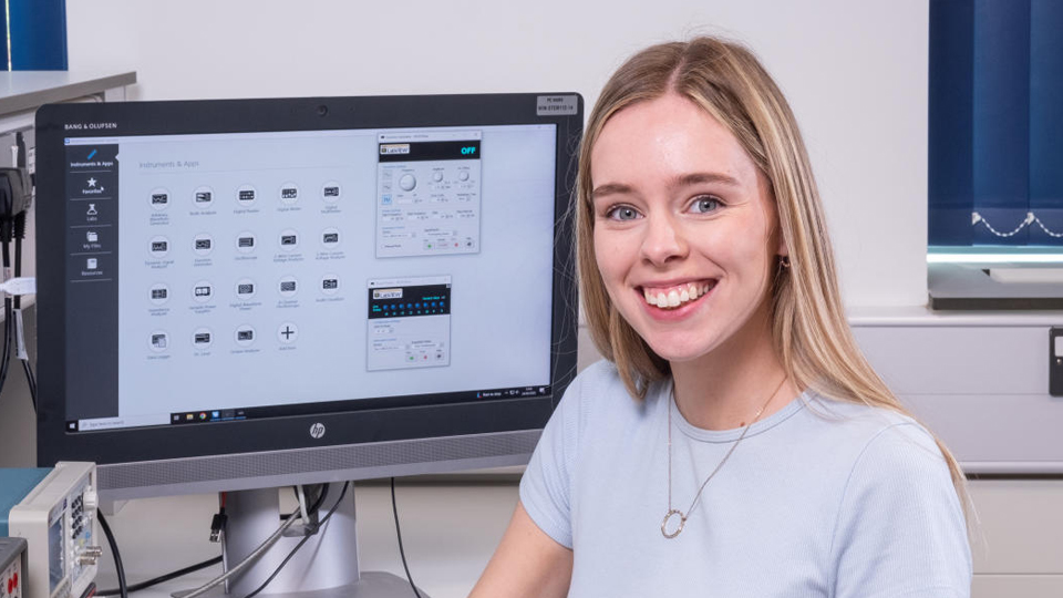 Olivia smiling at the camera with a computer in the background