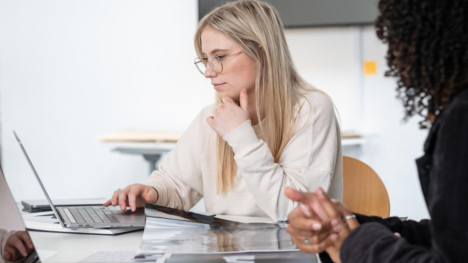 A student holding their chin and looking at their laptop